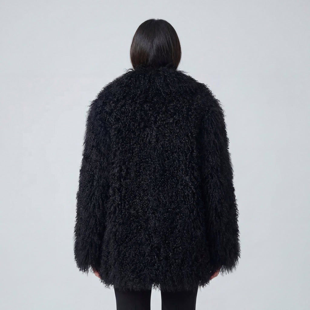 Model wearing a long black Mongolian fur coat with dense curly shearling texture – UK women’s winter outerwear
