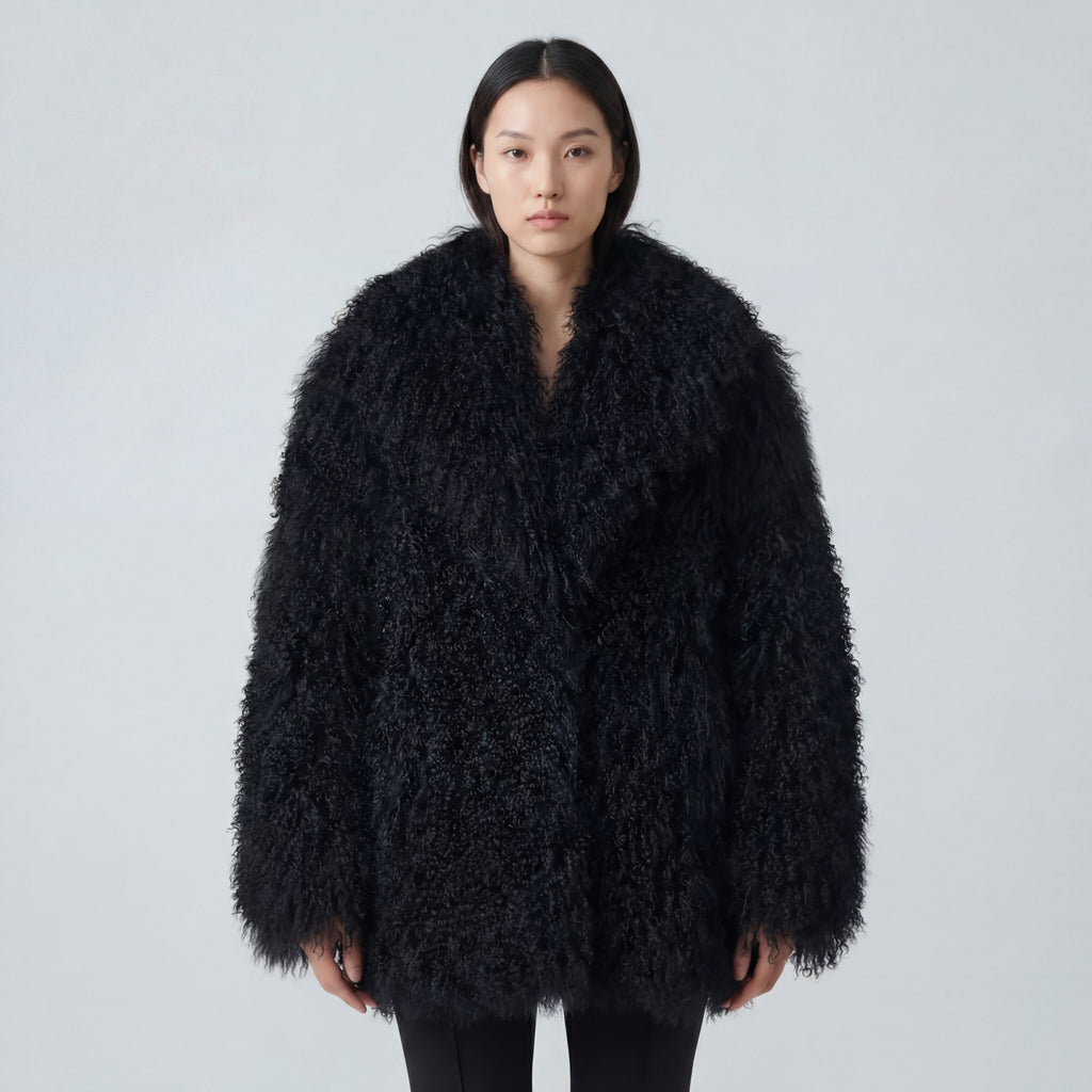 Model wearing a long black Mongolian fur coat with dense curly shearling texture – UK women’s winter outerwear
