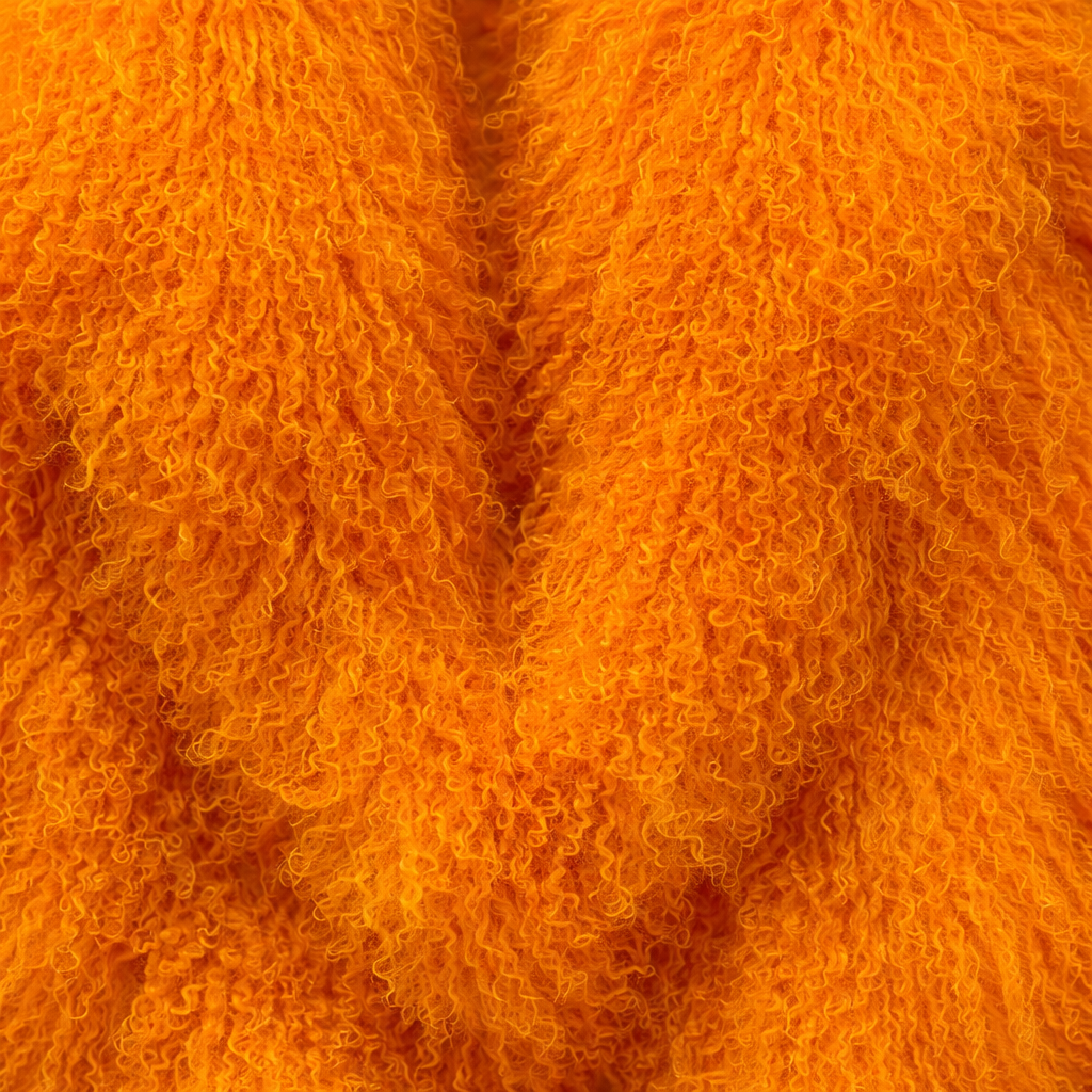 Close-up of orange Mongolian fur coat showing dense curly shearling texture – UK women’s winter outerwear