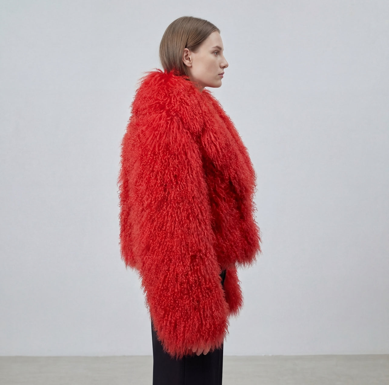 Model wearing a cropped red Mongolian fur coat with dense curly shearling texture – UK women’s winter outerwear